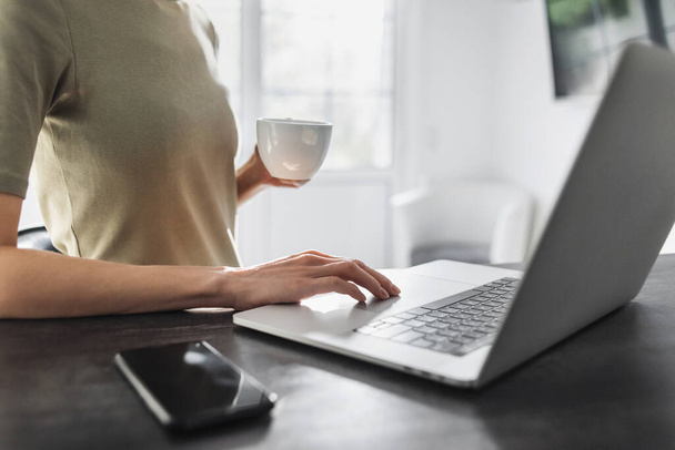Young woman using laptop computer and drinking coffee  - Foto, immagini