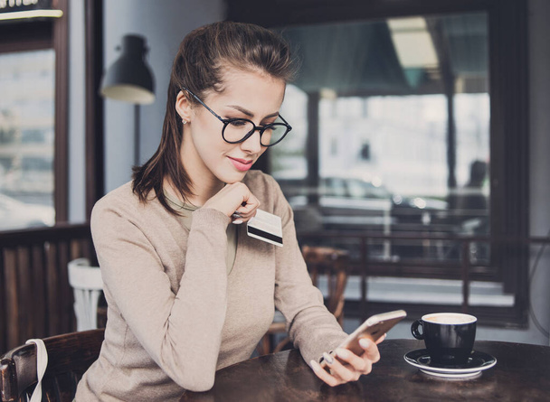 Young beautiful woman using smartphone in cafe shopping online  - Fotó, kép