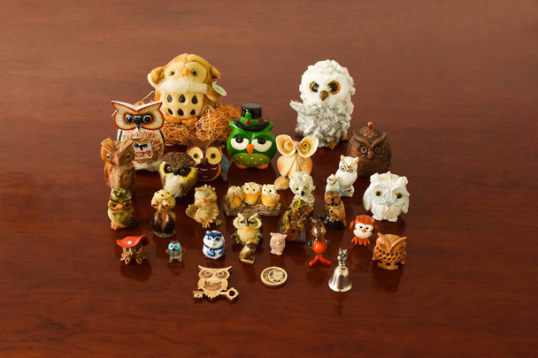 Figurines jouets de hiboux de différentes formes et tailles sur une table en bois
 - Photo, image