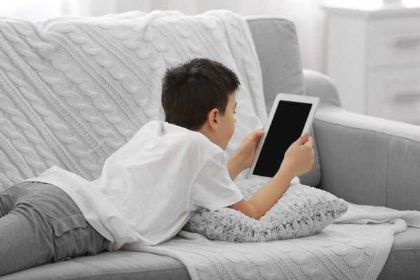 Chłopiec korzystający z tabletu na kanapie w domu - Zdjęcie, obraz