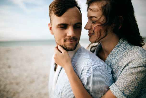 Woman hugs a man in their honeymoon on the sea beach - Photo, image