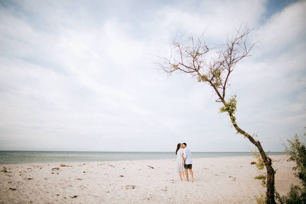 Young couple walks on a deserted sea beach. Summer vacation at sea - Fotoğraf, Görsel
