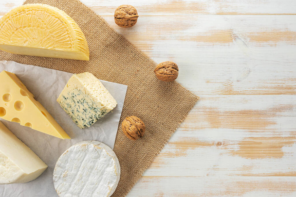 Sortiment verschiedener Käsesorten auf weißem Holztisch. Käse-Hintergrund. - Foto, Bild