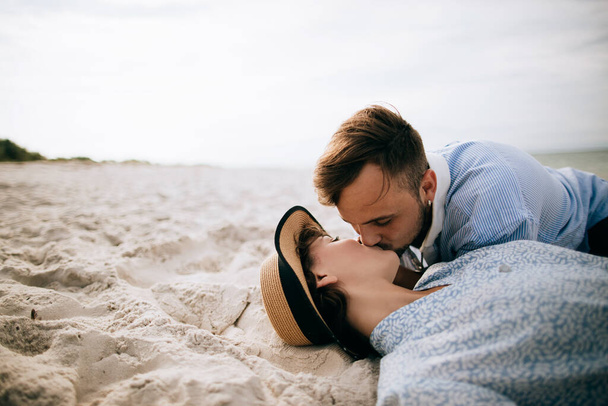 Young couple lying on the sand on the beach and kissing. Holidays at sea - Foto, Imagen