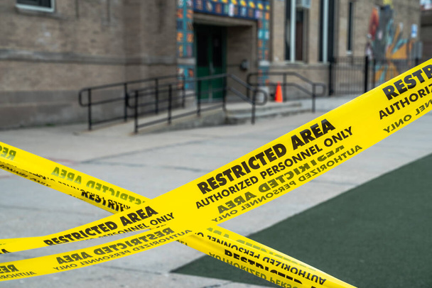 Widok z bliska na barierę w kształcie litery x na żółtym obszarze zastrzeżonym taśma ostrzegawcza blokująca plac zabaw w szkole w Chicago. - Zdjęcie, obraz