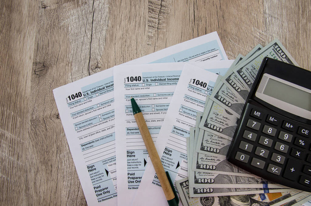 daňové formuláře 1040 s kalkulačkou, perem a dolary na dřevěném stole - Fotografie, Obrázek