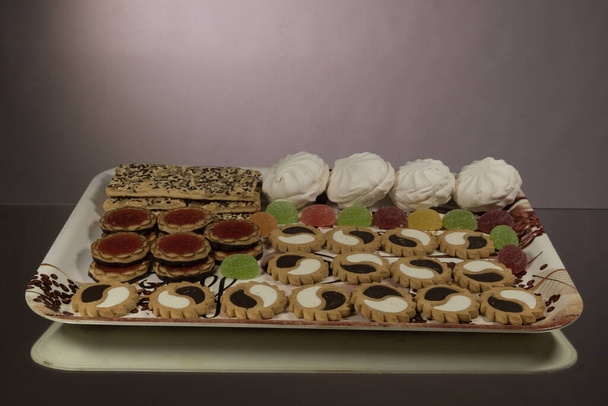 Assortiment de gâteaux au chocolat, confiture, marmelade, bouffées, guimauves sur un plateau. Pâtisserie
. - Photo, image