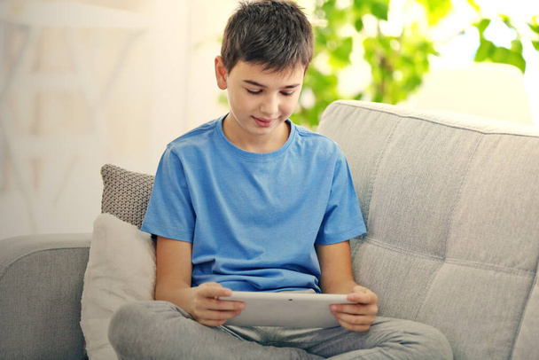 Niño usando la tableta en un sofá en casa
 - Foto, imagen