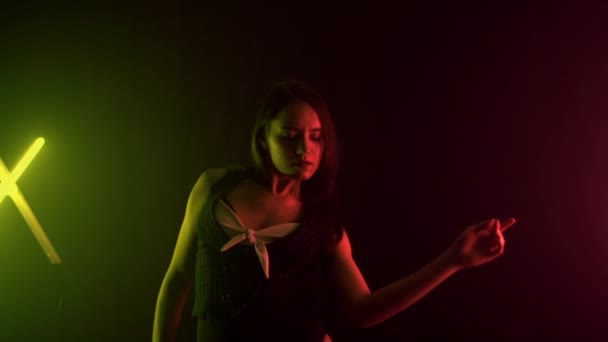 Beautiful young brunette girl in a nude outfit dancing in a studio with multi-colored light, background, slow motion - Footage, Video