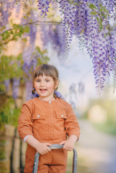 Girl under the blooming wisteria - Fotoğraf, Görsel