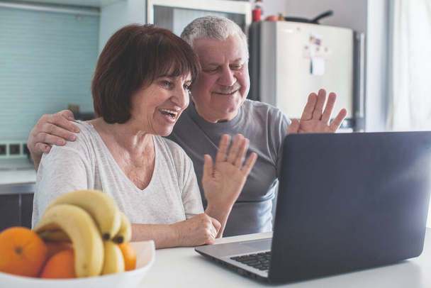 Älteres Ehepaar schaut in der Küche auf den Computer - Foto, Bild