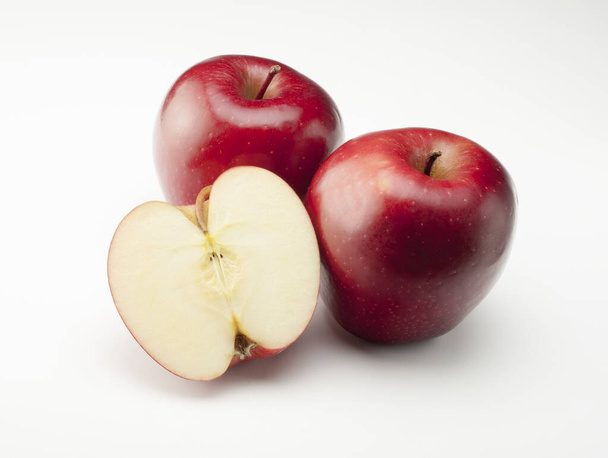 still life of two whole red apples and one cut in half on white background - Foto, Imagem