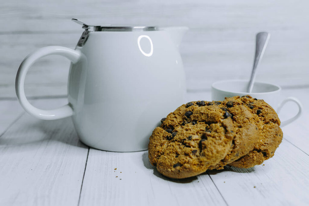 朝食用のチョコレートチップクッキー。お茶のティーポットとマグカップ - 写真・画像