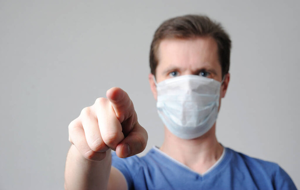 a man in a medical mask points a finger. requirement and recommendations of a doctor concept. you are next theme - Foto, imagen