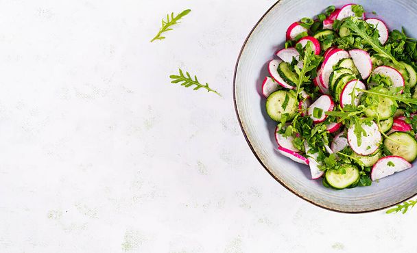 Ensalada vegetal vegetariana de rábano, pepinos, rúcula y cebolla verde. Comida vegana saludable. Vista superior, techo, suelo plano
 - Foto, Imagen