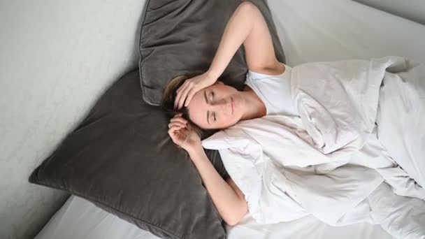 Attraktive lächelnde junge Frau streckt sich im Bett, wacht allein glücklich auf, wacht nach gesundem Schlaf in gemütlichen bequemen Bett und Matratze genießen Sie guten Morgen - Filmmaterial, Video