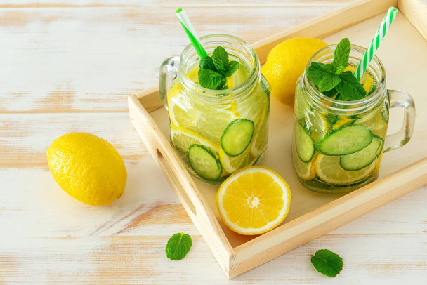 Detox water with sliced lemon and cucumber in a jar on wooden table. Healthy concept. - Fotoğraf, Görsel