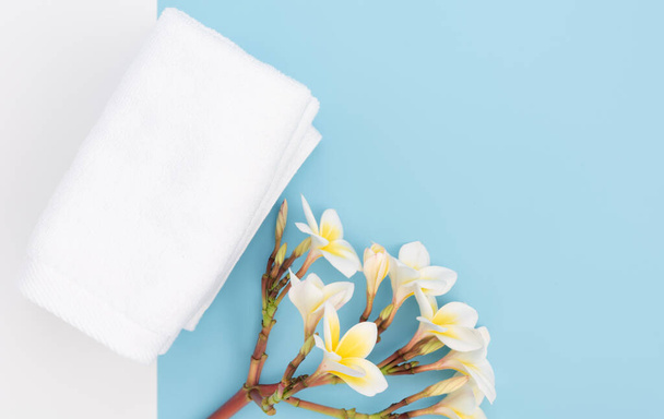 Beyaz havlu ve güzel frangipal ya da plumeria spa çiçeği mavi arka planda, düz yatıyordu - Fotoğraf, Görsel