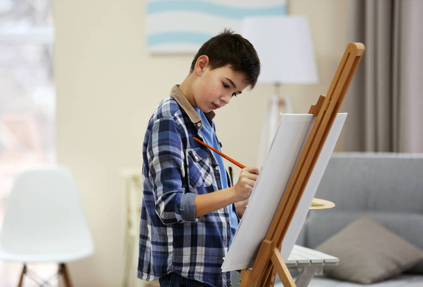 Boy drawing on an easel at home - Foto, afbeelding