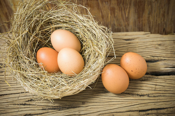 Eggs in straw basket on wood background. With copy space on the right side for writing text. - Foto, immagini