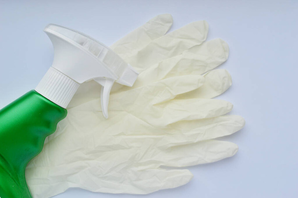 Guanti in gomma bianca e detergente in bottiglia verde su fondo bianco
 - Foto, immagini