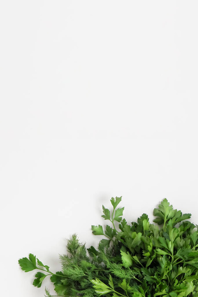 A large bunch of fresh organic green parsley, dill on a white background. Garden greens, spicy herbs, ingredients for cooking. Vertical. Close-up, top view, copy space. - Valokuva, kuva