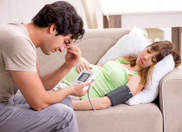 A férj ellenőrzi a terhes feleségek vérnyomását - Fotó, kép