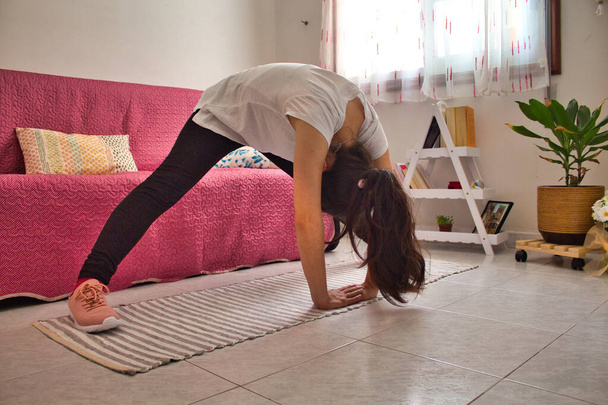Fiatal nő a nappaliban csinál jóga és meditáció sport divat. - Fotó, kép
