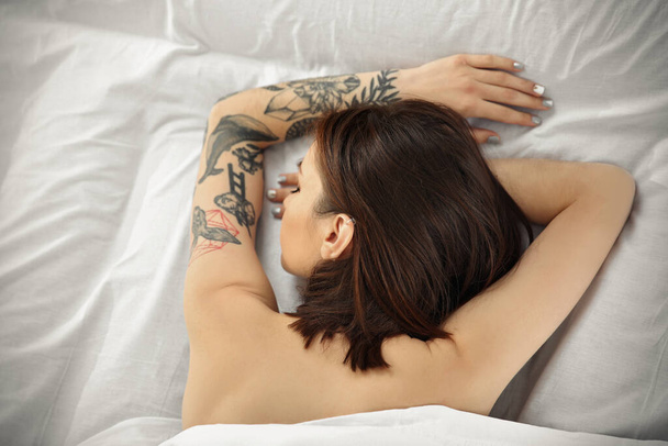 Donna attraente con tatuaggio sdraiato sul letto
 - Foto, immagini