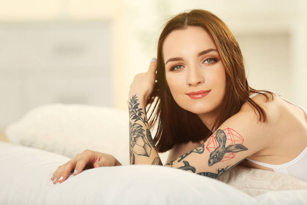 Mujer atractiva con tatuaje acostado en la cama
 - Foto, imagen