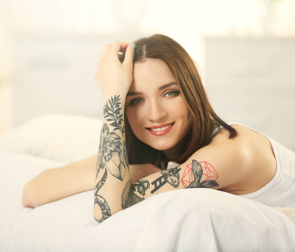 Mujer atractiva con tatuaje acostado en la cama
 - Foto, imagen