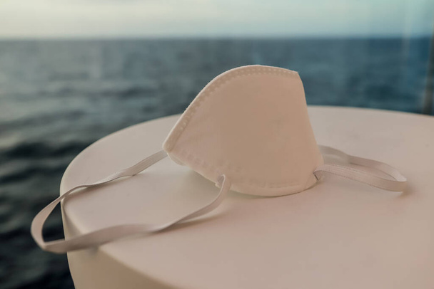 La máscara médica sobre la mesa sobre el fondo de mar. Concepto de prevención, Cuarentena, COVID-19
. - Foto, imagen