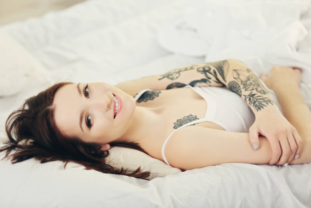 Attractive woman with tattoo lying on the bed - Fotó, kép