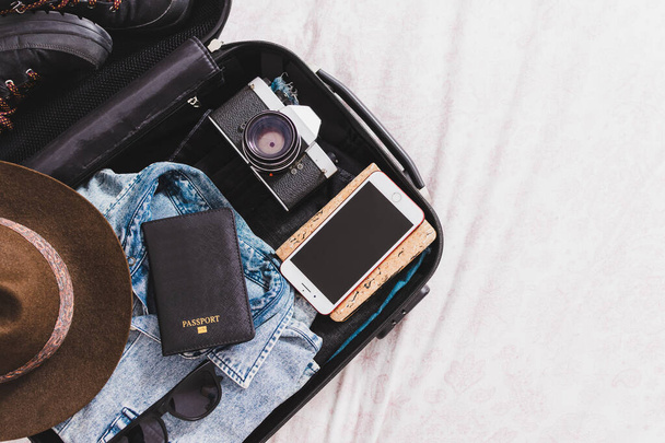 nyitott bőrönd útlevéllel, fényképezőgéppel, sapkával, szemüveggel és ruhával - Fotó, kép