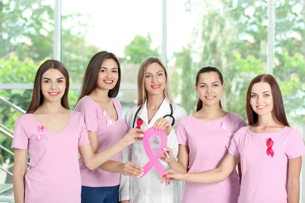 Female doctor and girls with pink ribbon. Breast cancer concept - Фото, зображення