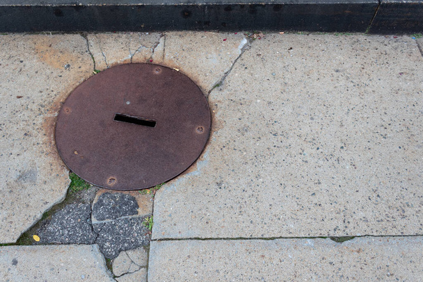 Korozivzdorná kovová kulatá krycí deska na popraskaném chodníku z betonu a asfaltu, kreativní kopírovací prostor, horizontální vzhled - Fotografie, Obrázek