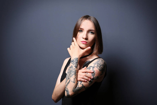 Belle jeune femme avec tatouage posant sur fond gris
 - Photo, image
