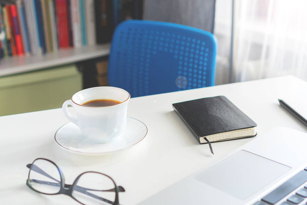 koffiebeker en laptop staan op het bureaublad op een zonnige dag - Foto, afbeelding