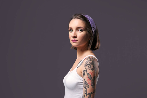 Mulher bonita com tatuagem posando no fundo cinza
 - Foto, Imagem