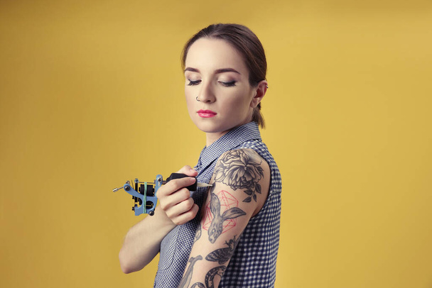 Gyönyörű fiatal nő tetoválás magát, és pózol a sárga háttér - Fotó, kép