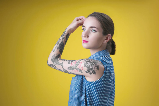 Mulher bonita com tatuagem posando no fundo amarelo
 - Foto, Imagem