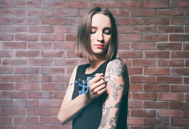 Krásná mladá žena tetování sama na cihlové zdi pozadí - Fotografie, Obrázek