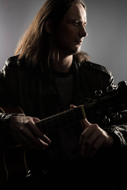 Επαγγελματίας μουσικός με ακουστική κιθάρα σε γκρι φόντο. Πυροβολήθηκε στο στούντιο - Φωτογραφία, εικόνα
