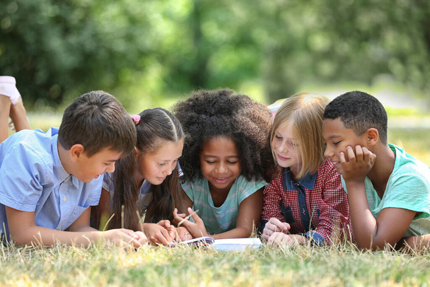 Yeşil çimenler üzerine kitap okuyan sevimli çocuklar. - Fotoğraf, Görsel