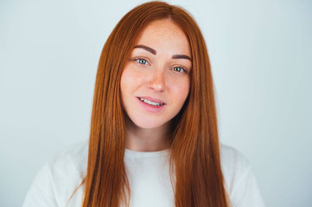portrait of redheaded young smiling woman looking positive standing on isolated white backgroung, style and beauty concept. - Photo, Image