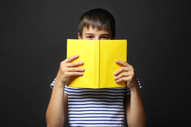 Cute boy reading book on grey background - Photo, Image