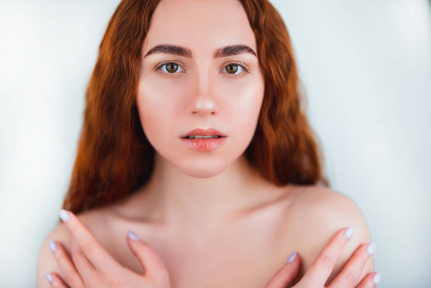 portrait of redheaded young sexy woman looking natural covering her body with both hands on isolated white backgroung, style and beauty concept. - Photo, image