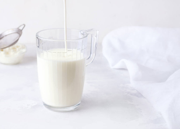 Ферментований молочний напій кефір наливають у склянку на білому тлі
. - Фото, зображення