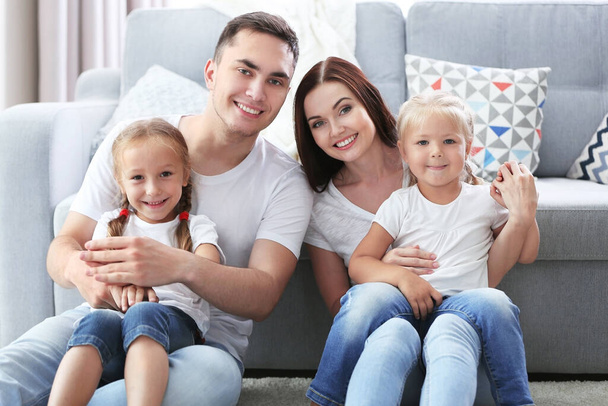 Happy parents with daughters near couch - Foto, Imagen