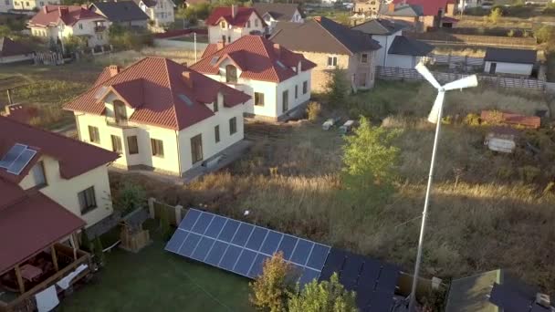 Вид с воздуха на жилой частный дом с солнечными батареями на крыше и ветрогенератор. - Кадры, видео
